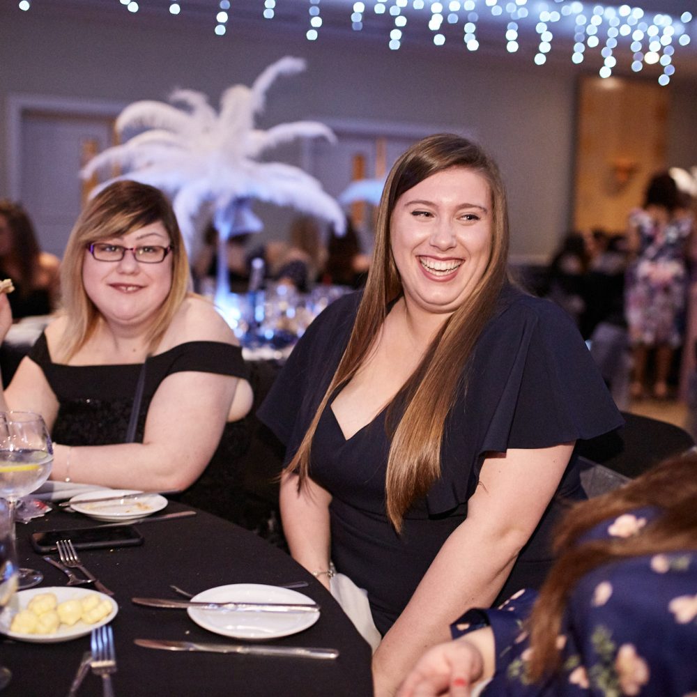 Guests smiling at a table decorated with white feather centrepieces