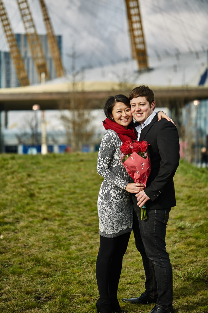 Newly engaged couple smiling together on a grassy bank in London