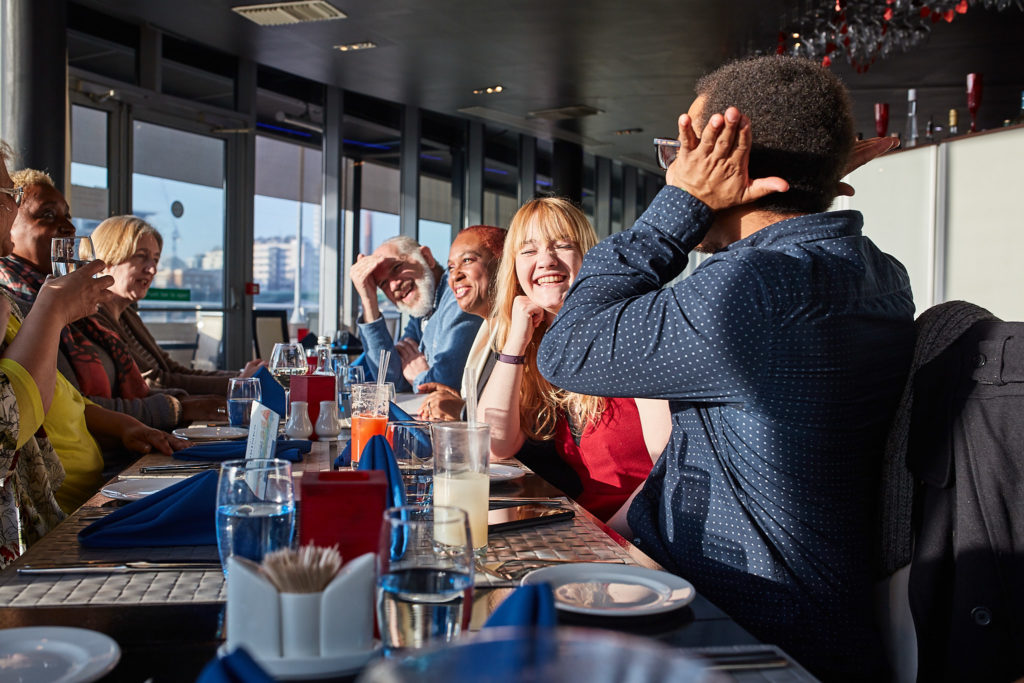 Guests seated along a long table at a 60th birthday lunch by the Thames