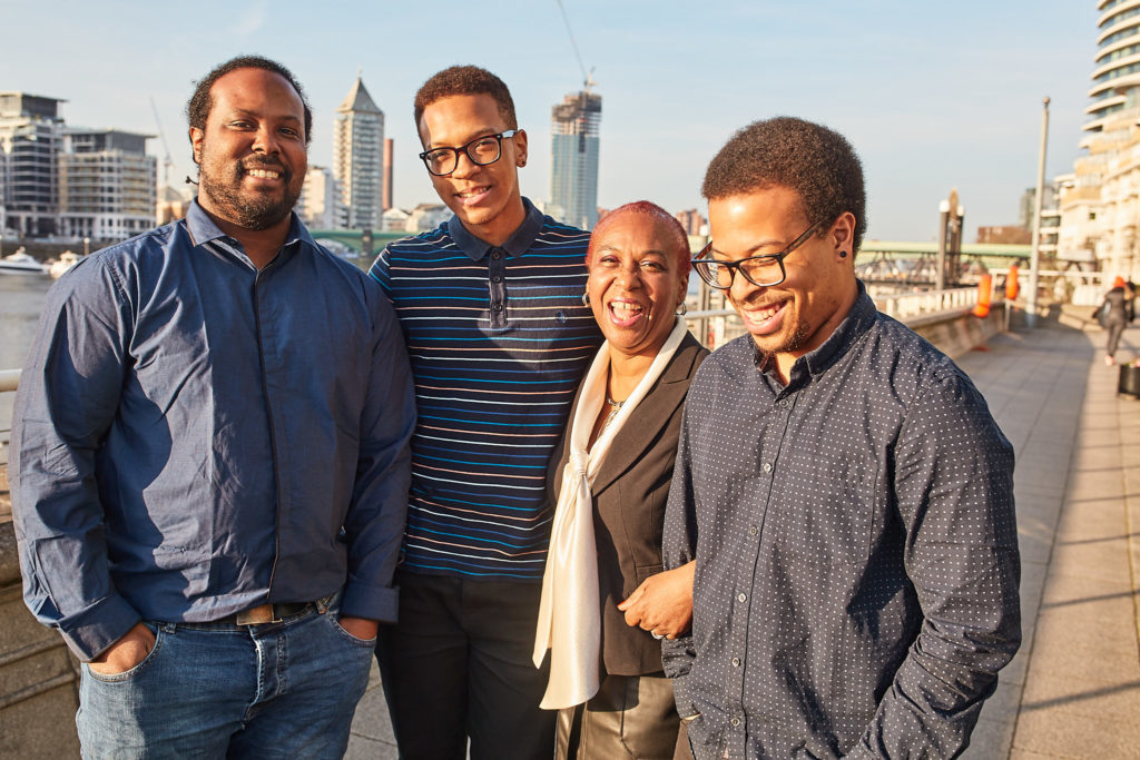 Four family members smiling together on the riverside terrace