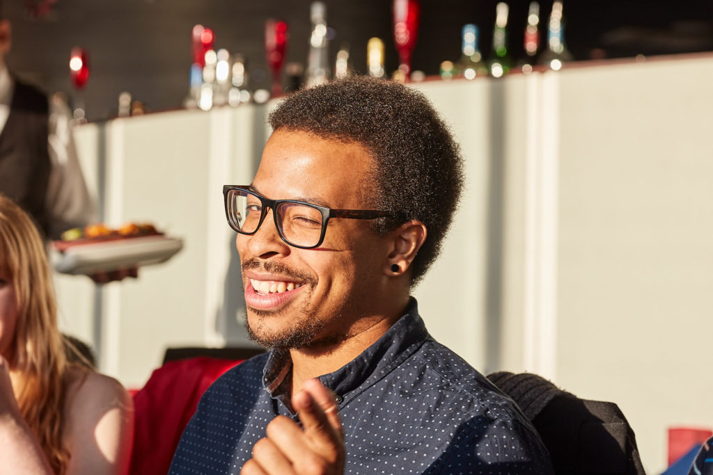 Guest in glasses and a dark shirt laughing at the table