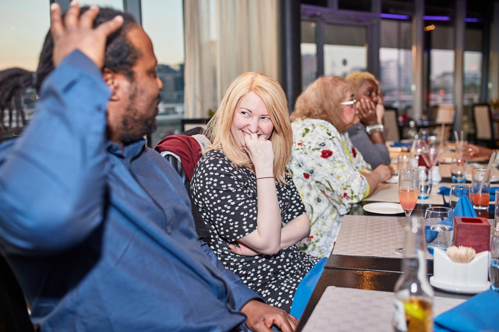 Guests laughing as one covers his face at the table