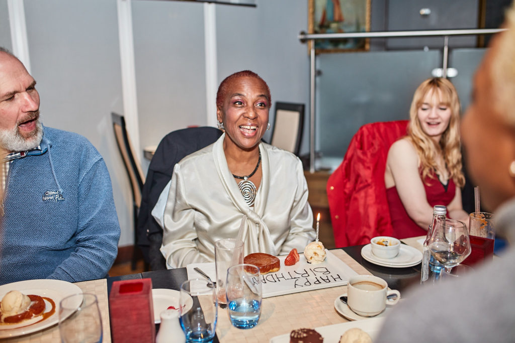 Guest in a cream jacket smiling at the birthday table