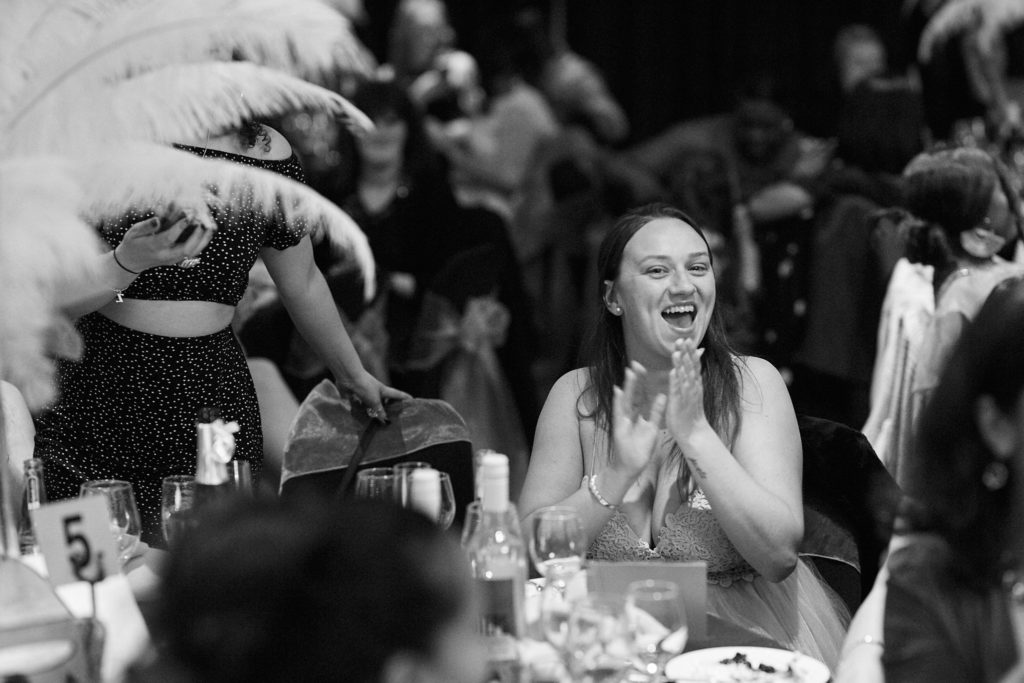 Black and white photo of a guest applauding at her table during the awards evening
