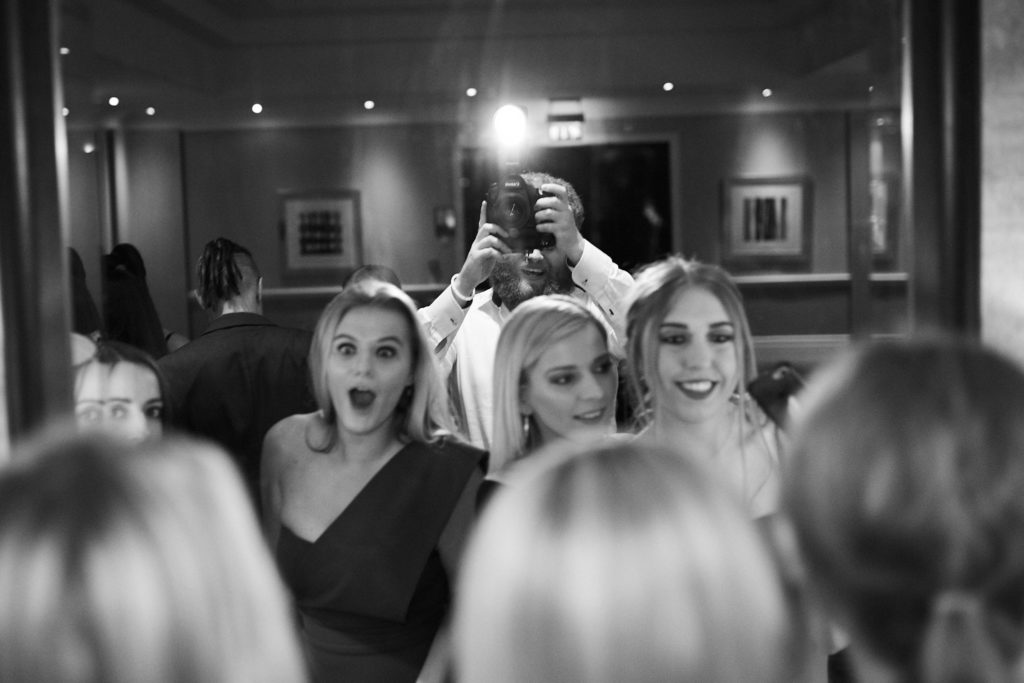Black and white photo of guests cheering at their table