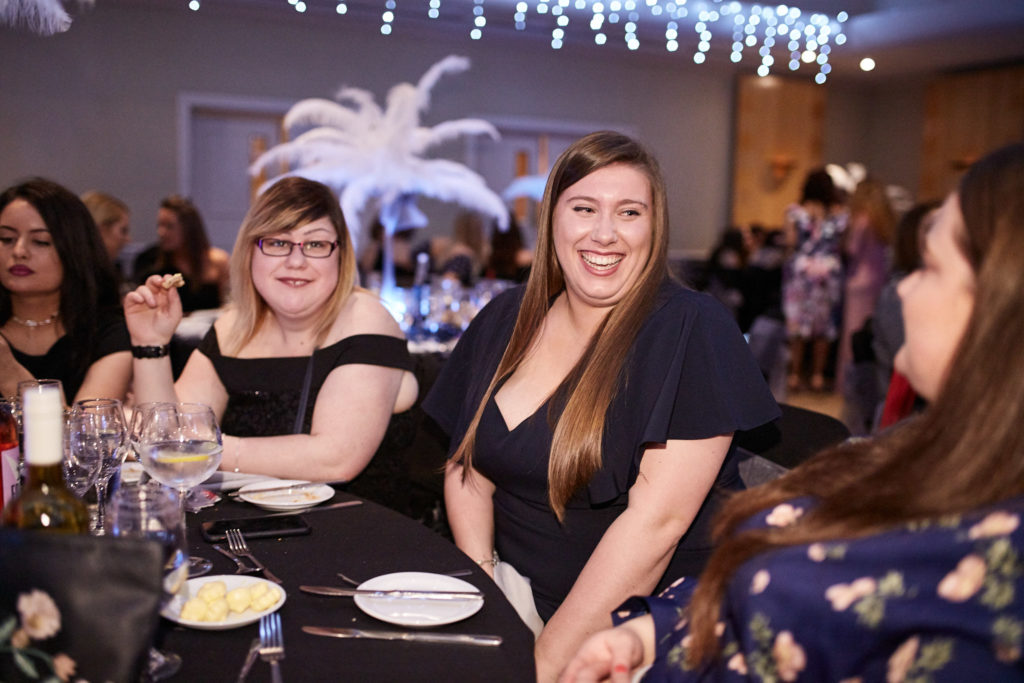 Guests smiling at a table decorated with white feather centrepieces