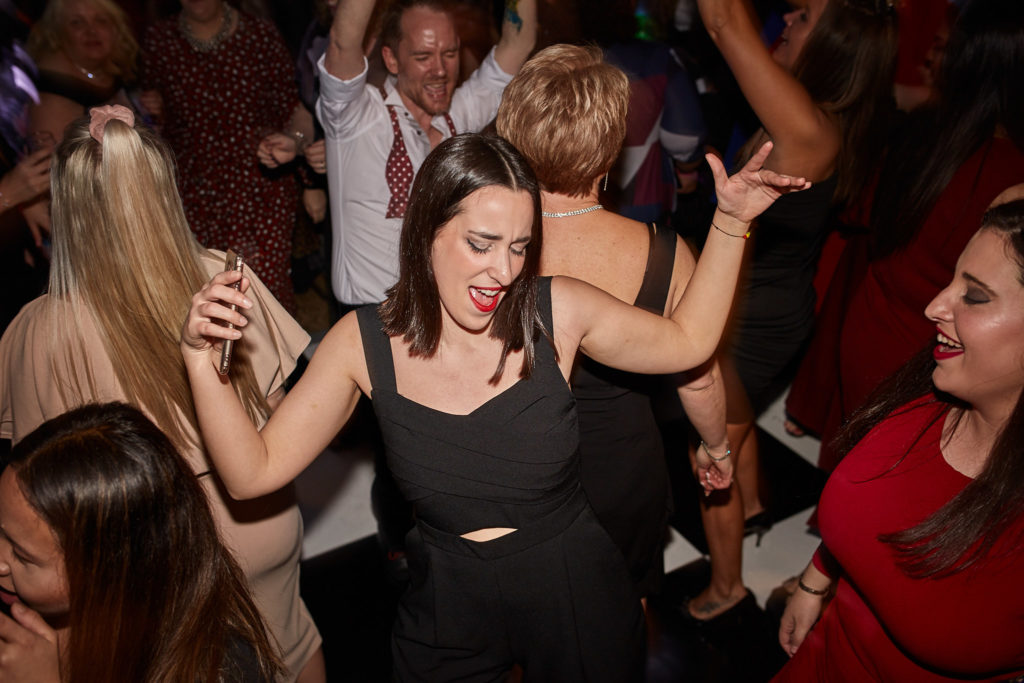 Guest dancing with her arms raised among the crowd