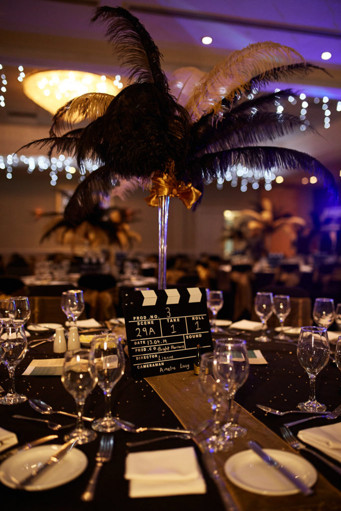Black ostrich feather centrepiece and a clapperboard on a film themed awards table