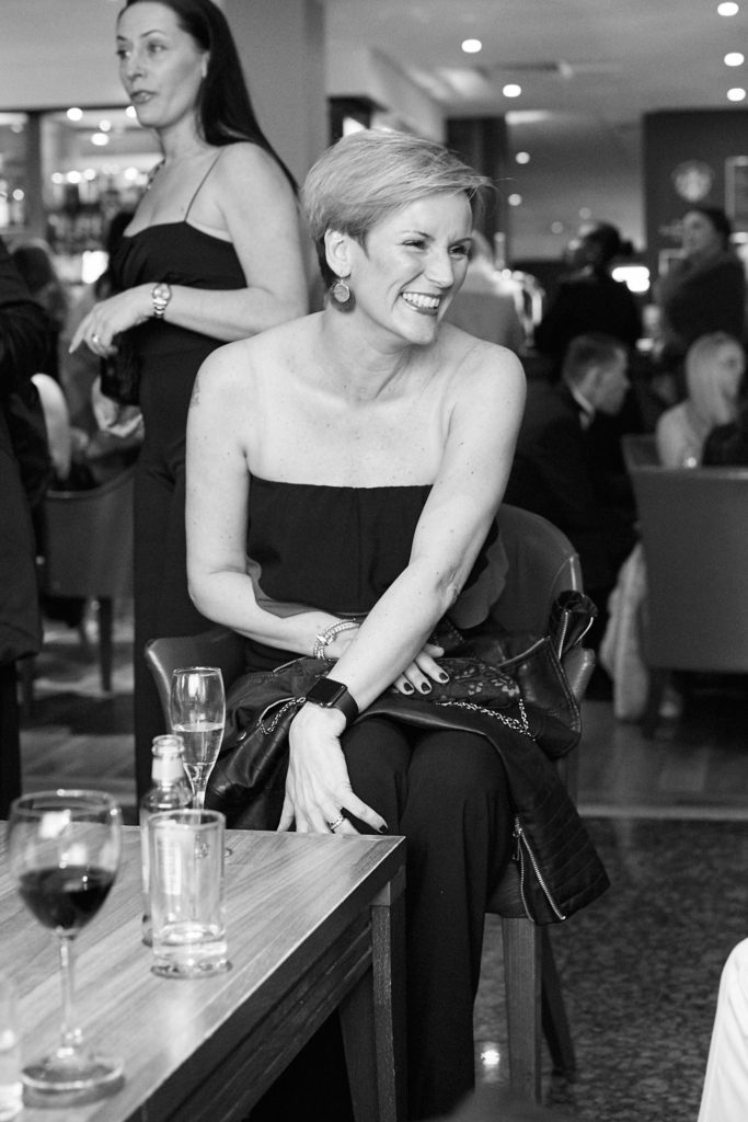 Black and white photo of a guest laughing as she sits in the hotel bar