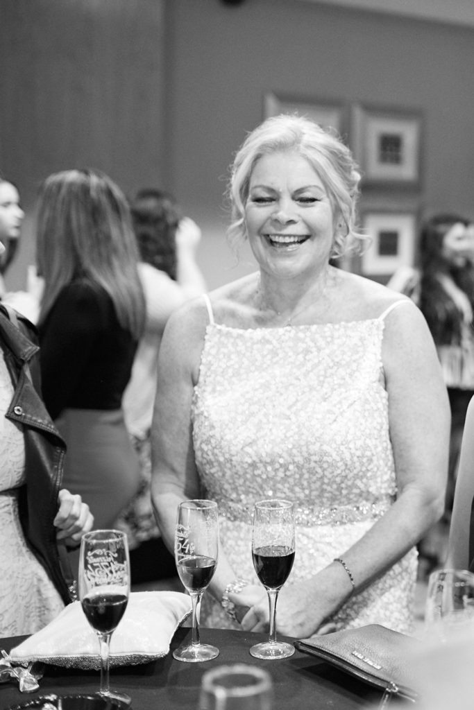 Black and white photo of a guest in a sequinned dress laughing at her table