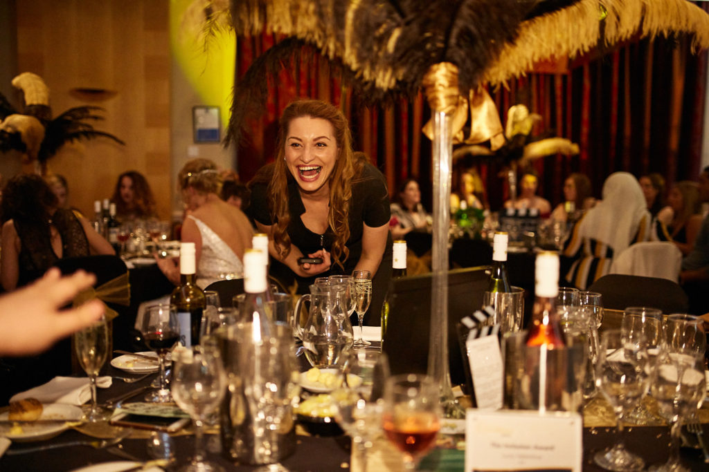 Guest laughing at a table decorated with gold and black feathers