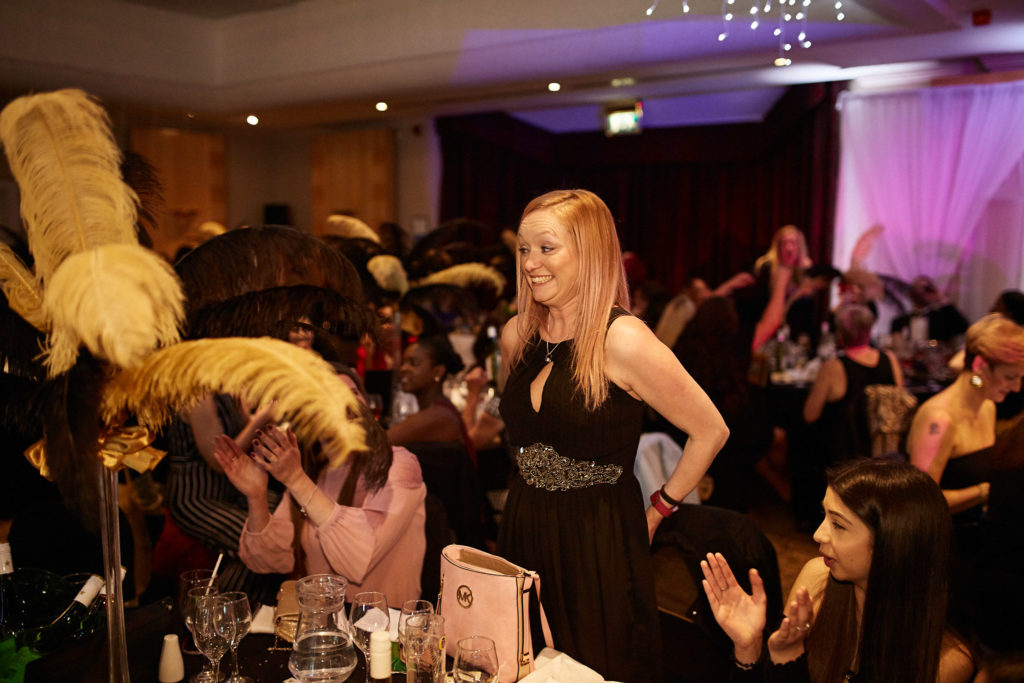 Award winner walking between the tables as guests cheer
