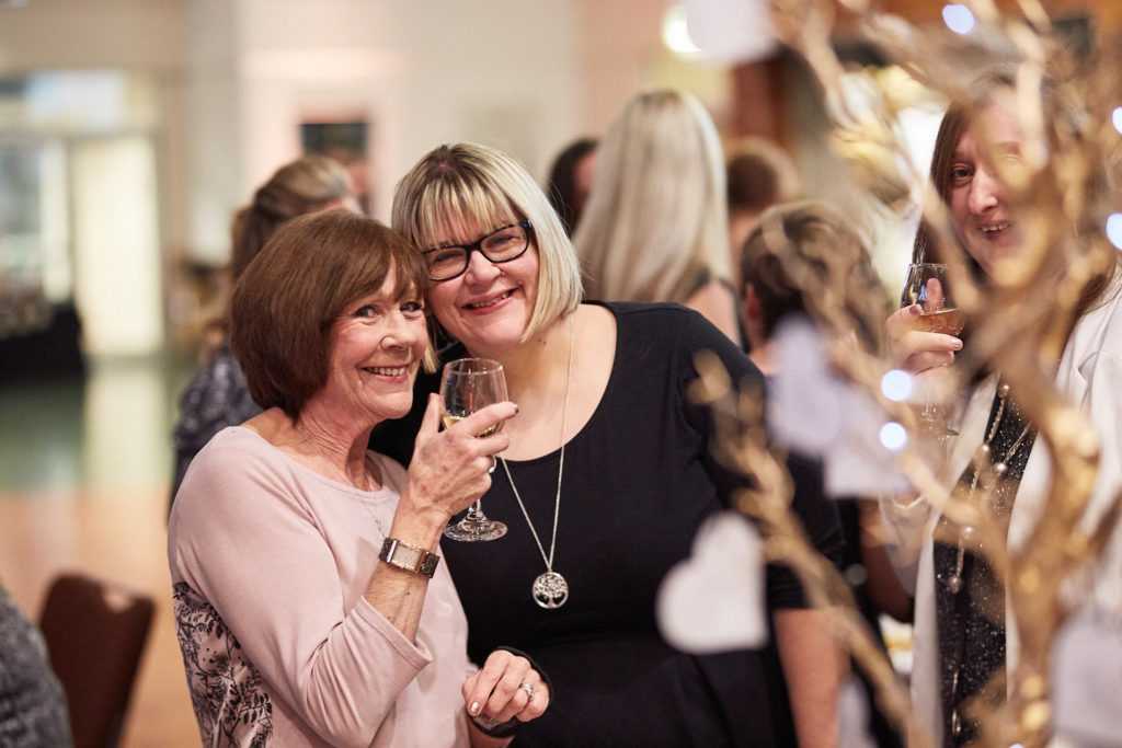 Two guests smiling together with a glass of fizz