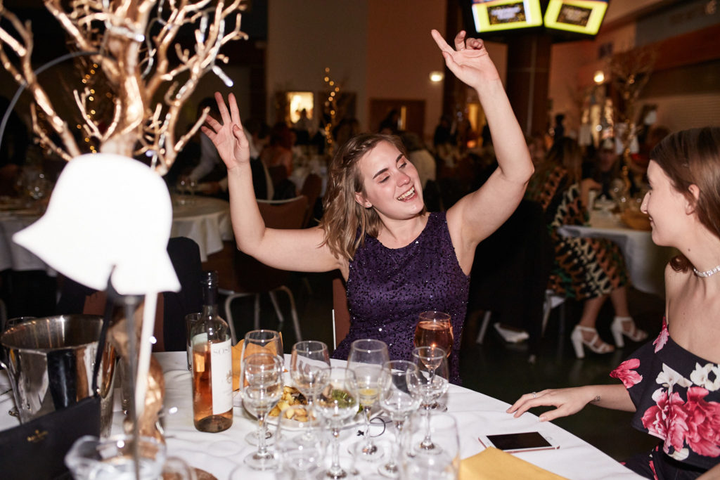 Guest cheering with her arms in the air at the table