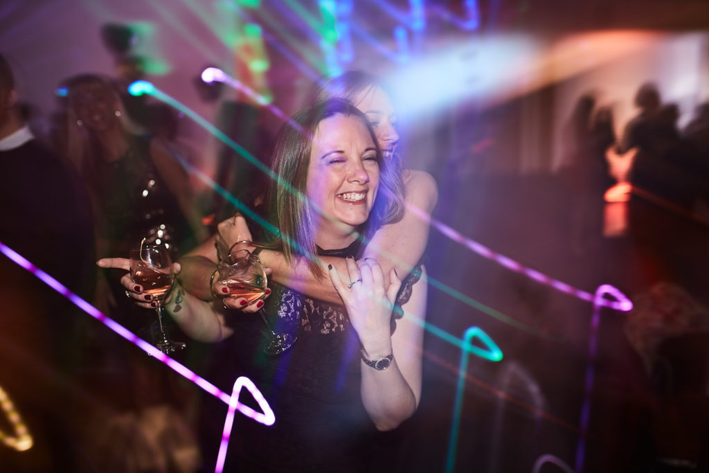 Guest dancing with a drink among streaks of coloured light