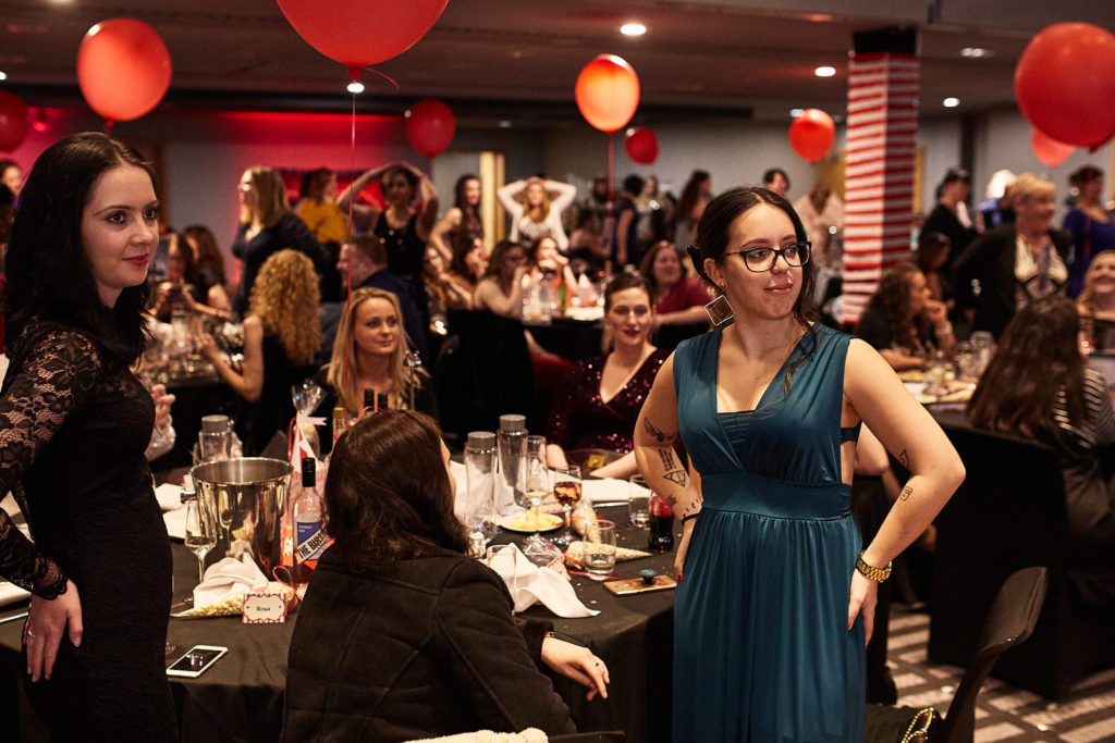 Guest in a teal dress standing to applause at her table