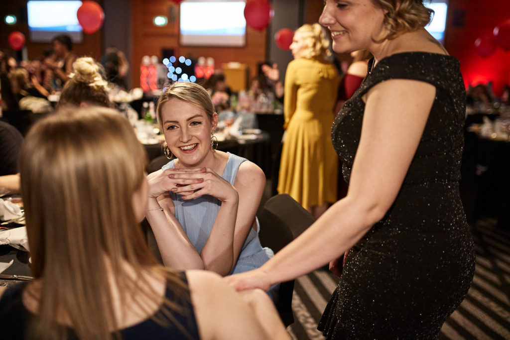Guest laughing at her table as a colleague leans in to talk