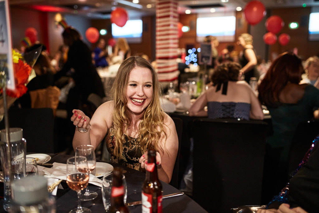 Guest smiling at her table under red balloons