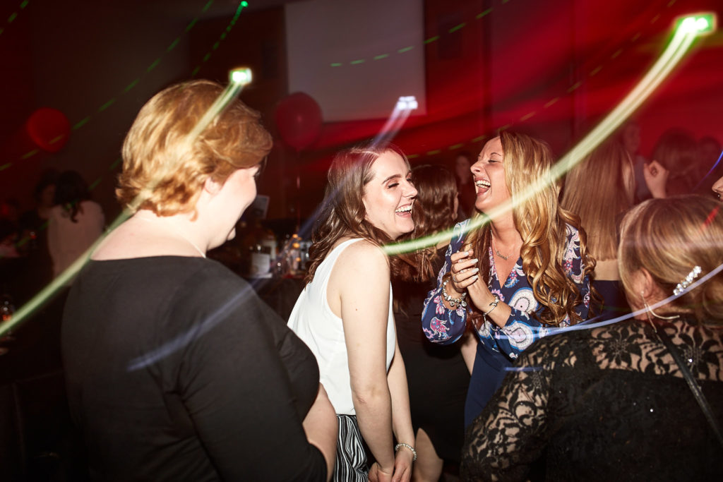 Guests dancing among trails of light under red lights