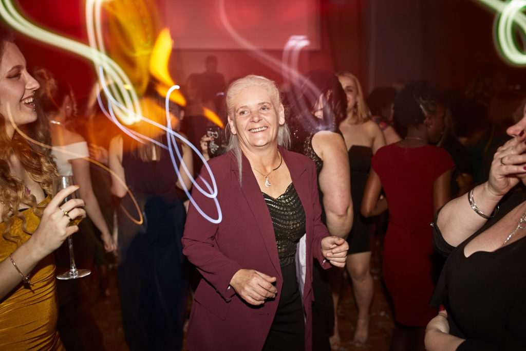 Guest in a burgundy jacket dancing with a drink