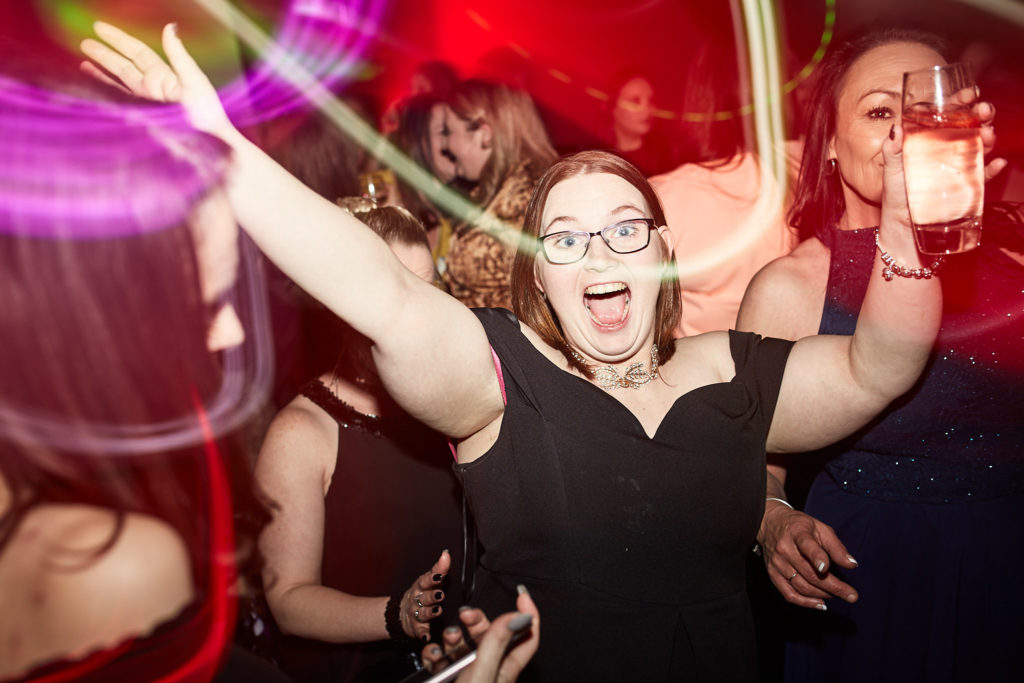 Guest dancing with her arms flung out as friends cheer