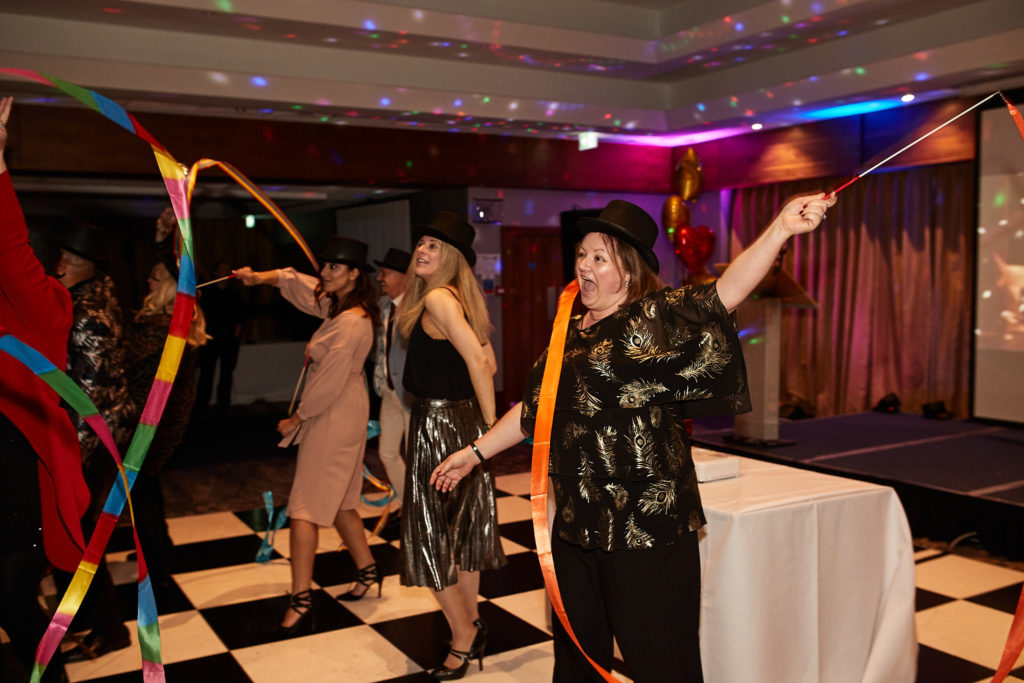 Guests dancing across the chequered dance floor with ribbons and hoops