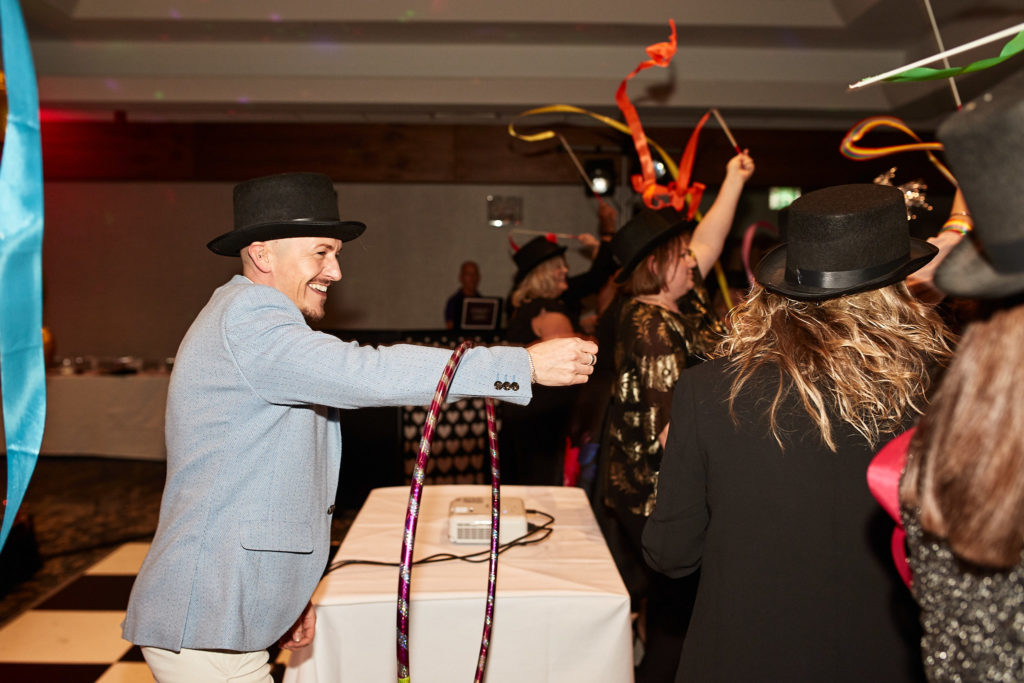 Guest in a top hat and blue jacket dancing with a hula hoop