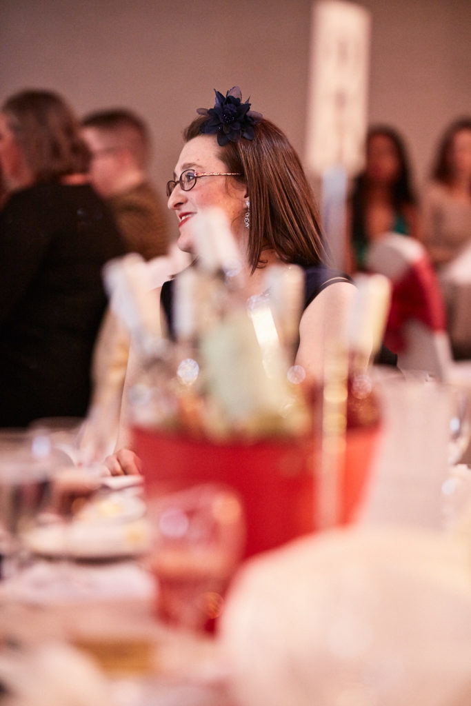 Guest in a fascinator smiling at her table behind the table decorations
