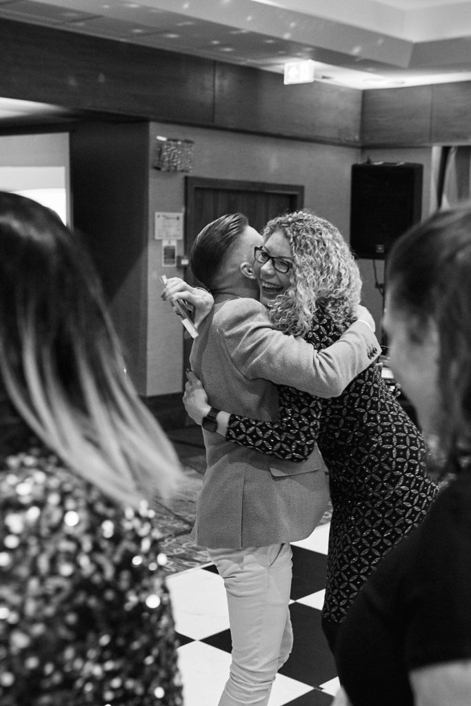 Black and white photo of two guests hugging on the dance floor