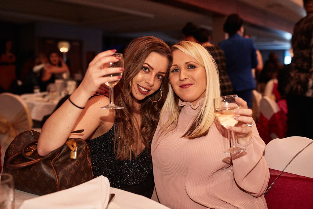 Two guests raising their glasses at the table
