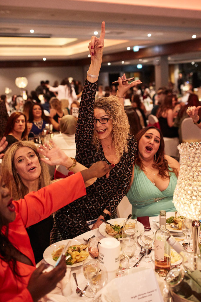 Guests cheering at their table, one pointing in the air