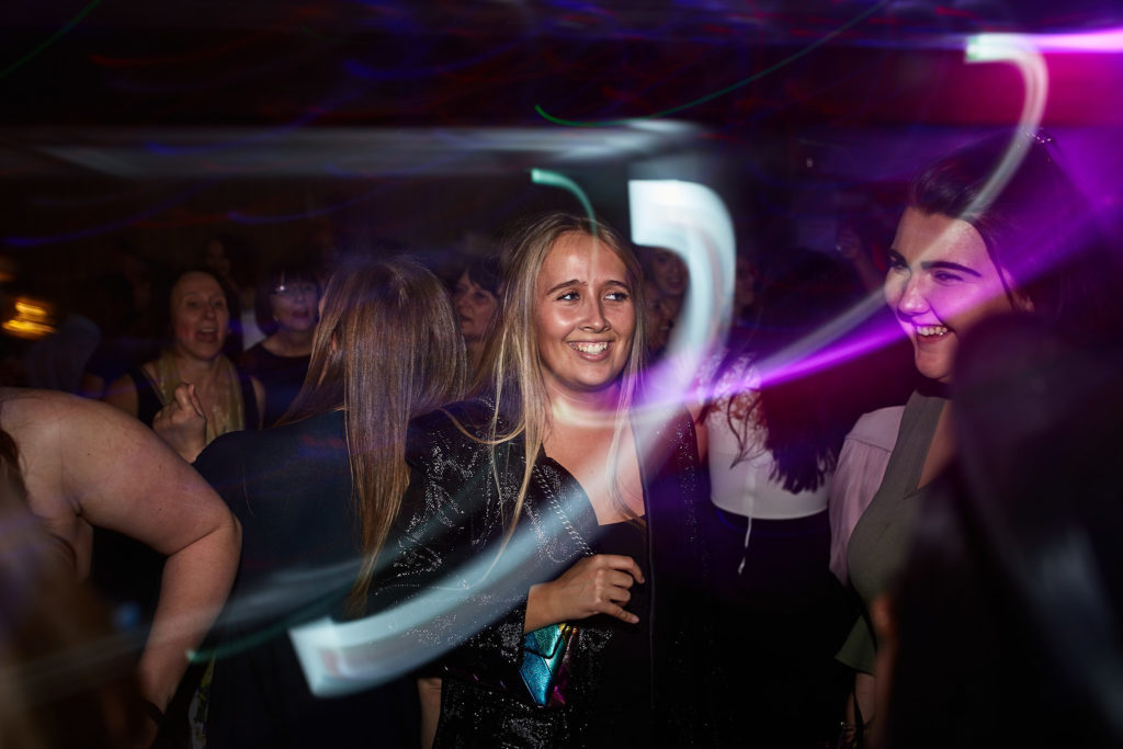 Guest dancing with a drink among streaks of white light