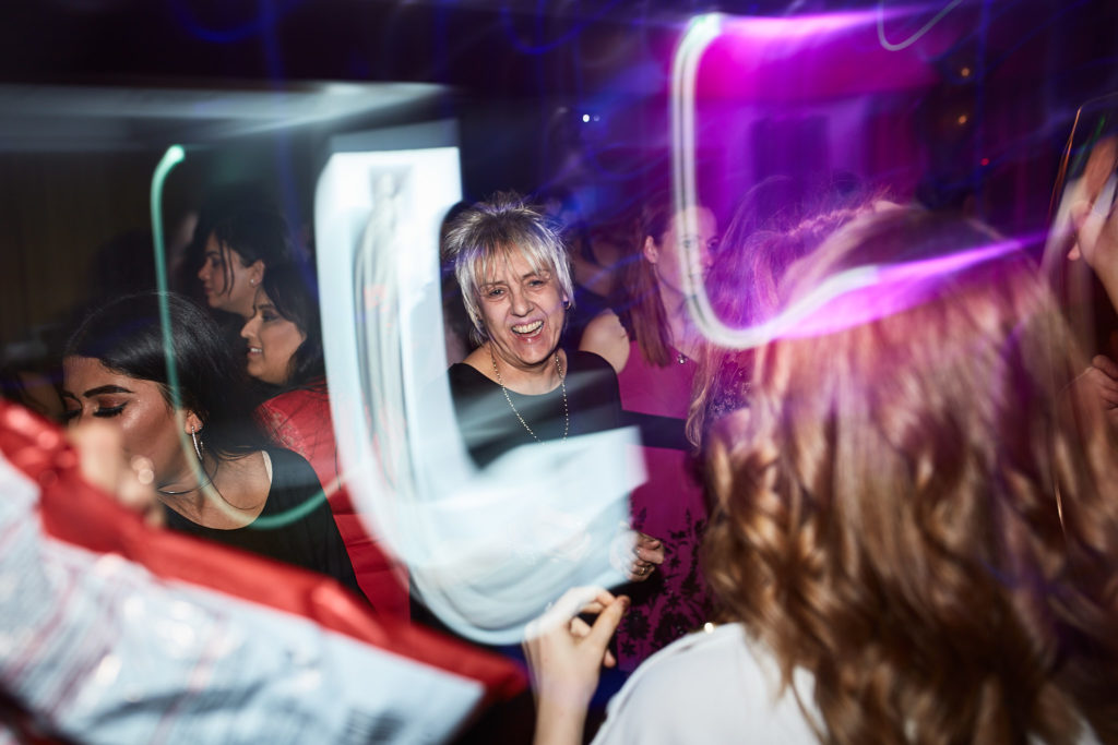 Guests dancing under purple lights and light trails