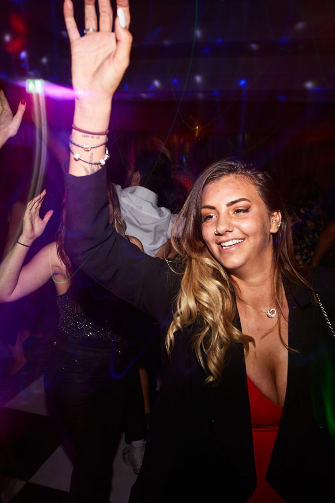Guest dancing with her arm in the air under purple lights