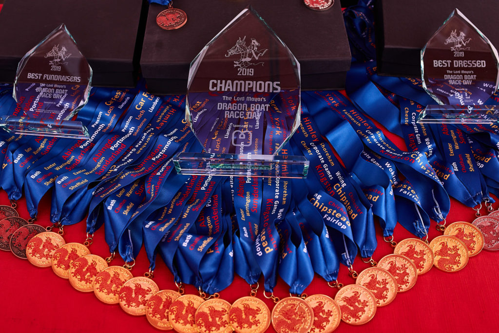 Glass trophies and blue medals laid out on a red table