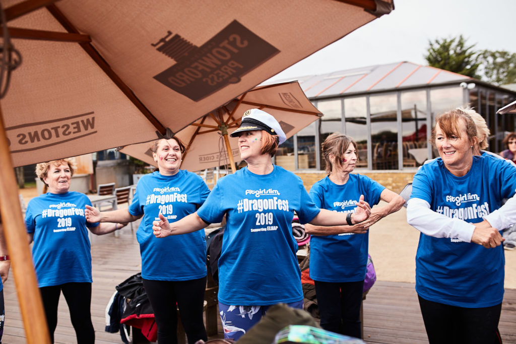 Team in matching blue T-shirts cheering under a parasol