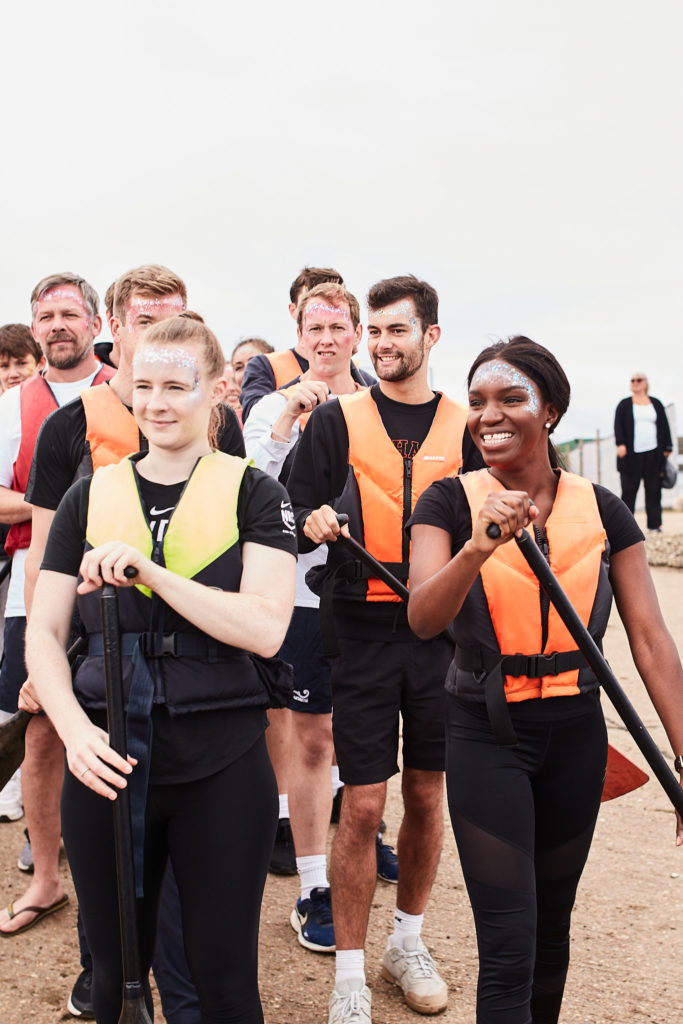 Paddlers in life jackets waiting on the shore with their paddles