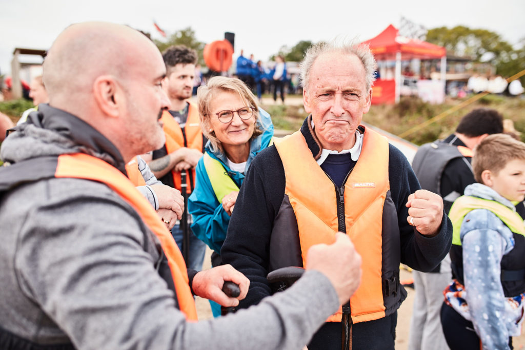 Man in an orange life jacket fist-bumping a team mate