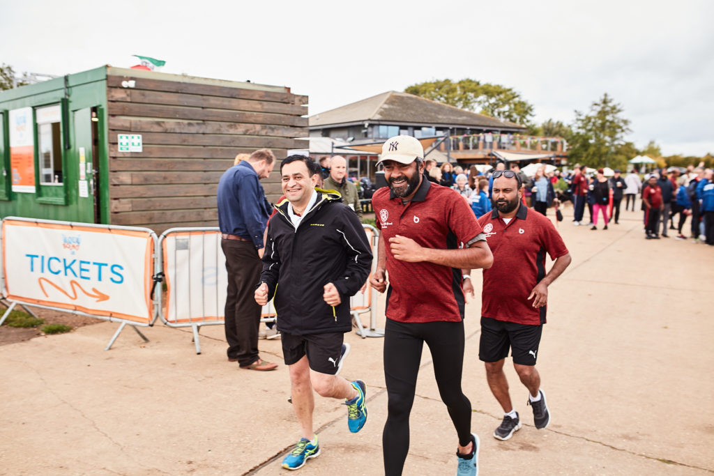 Three men jogging along the lakeside path