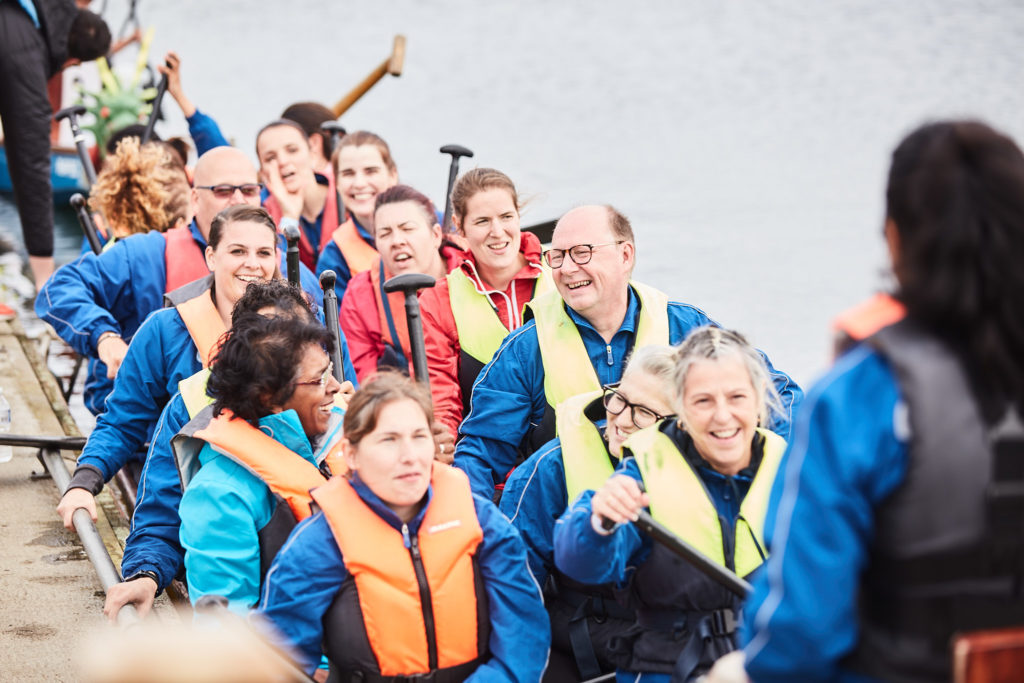 Dragon boat crew in blue cheering from their boat