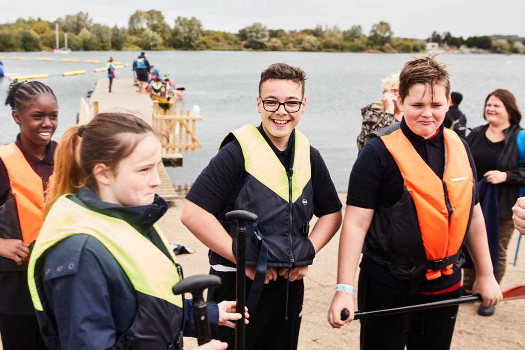 Young paddlers in life jackets waiting beside the lake
