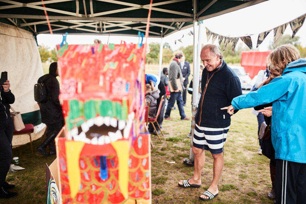 Children's painted cardboard dragon on display in a marquee