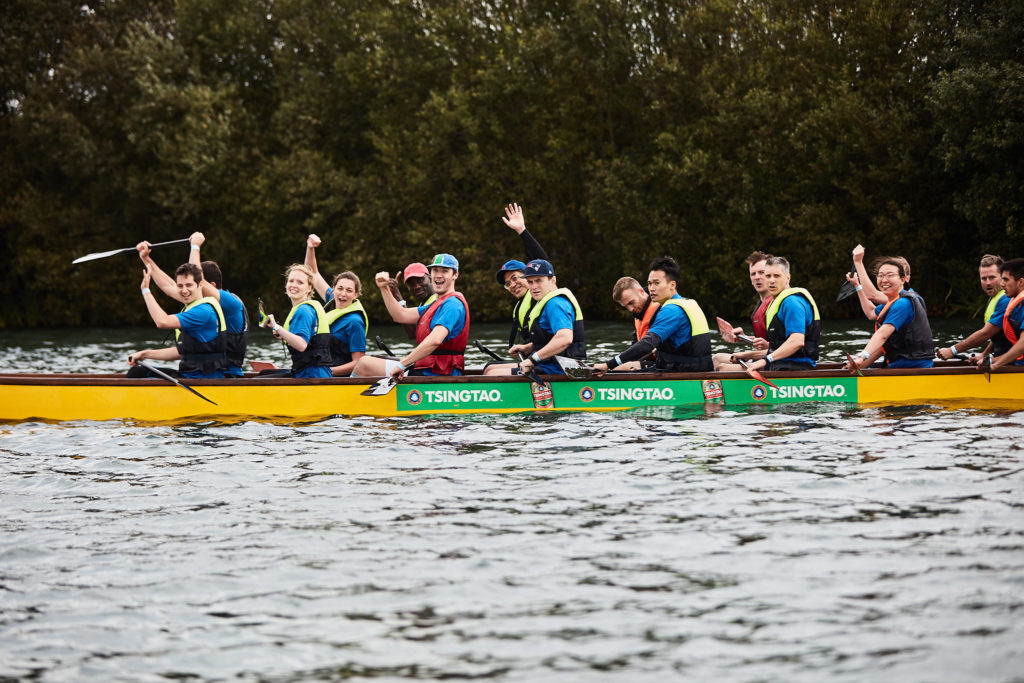 Dragon boat crew celebrating with their paddles in the air on the water