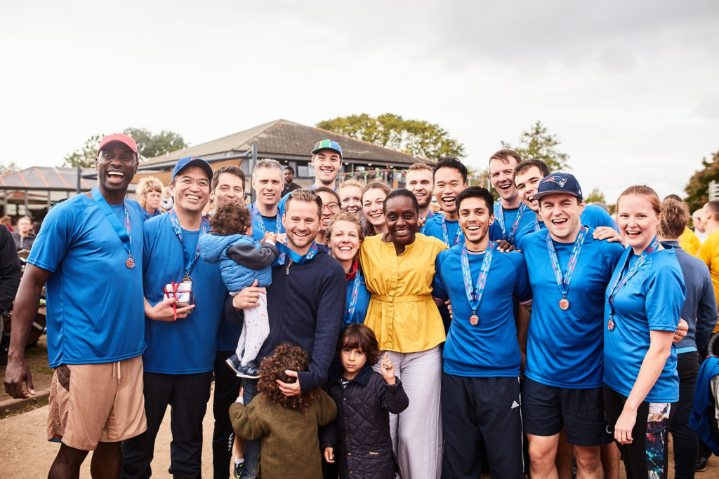 Winning team in blue shirts posing with their medals beside the lake
