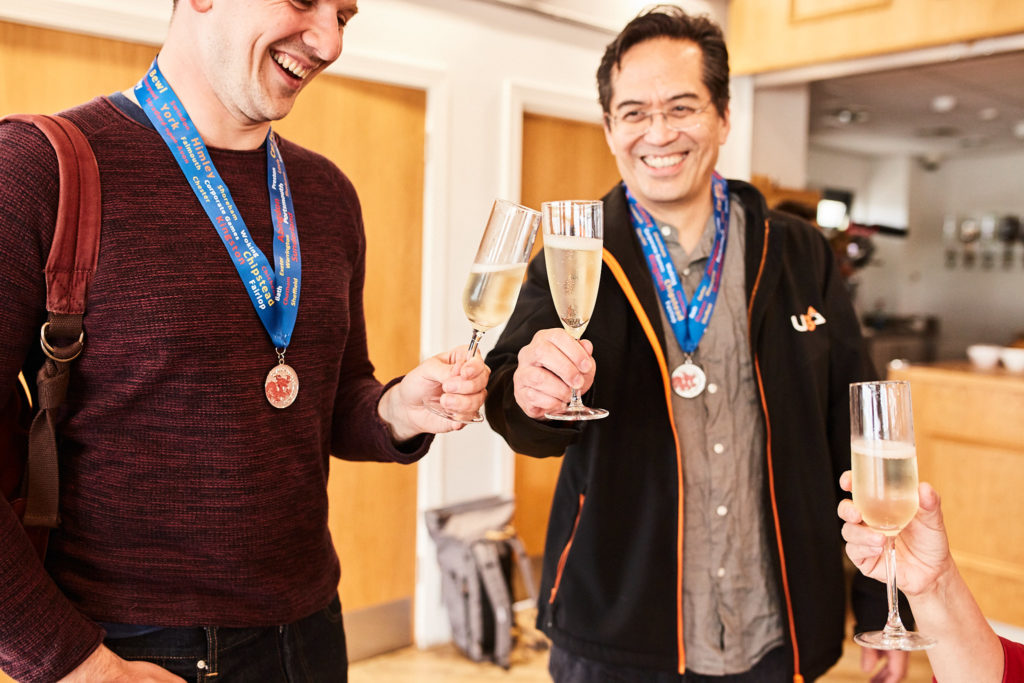 Two men wearing medals toasting with glasses of fizz