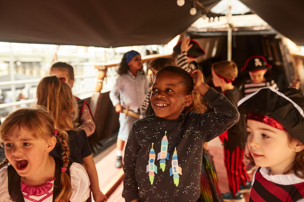 Children in pirate costumes cheering at a pirate birthday party aboard the Golden Hinde