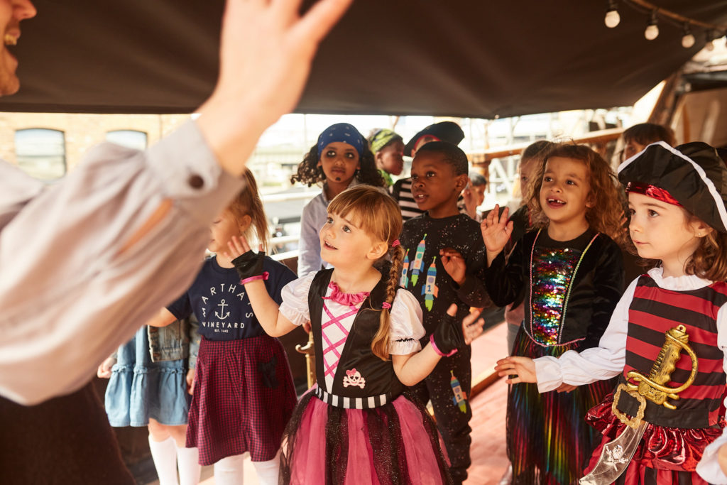 Children in pirate costumes watching the entertainer on the deck of the Golden Hinde