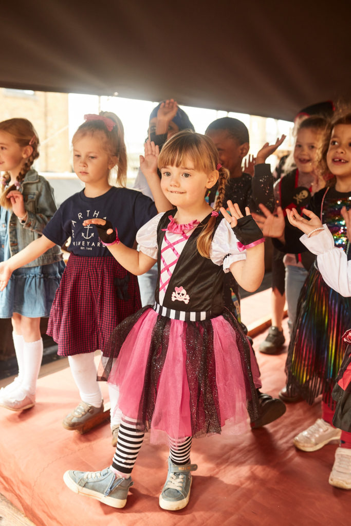 Girl in a pink pirate skirt laughing with other children on deck