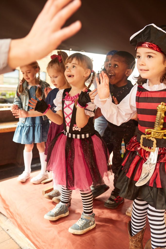 Children in pirate costumes clapping on the deck of the ship