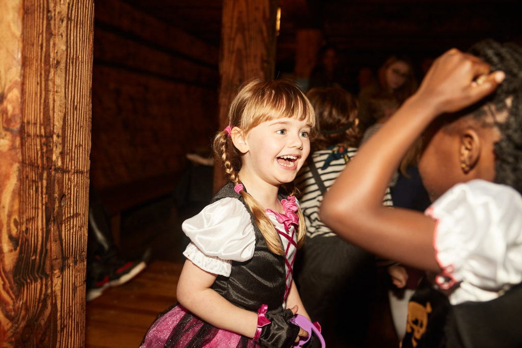 Girl in a pirate costume laughing below deck